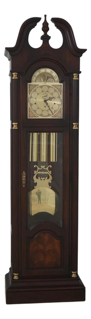 Chippendale Style Mahogany Longcase Clock with Beveled Glass and Brass Movement: Chippendale Style Mahogany Longcase Clock with Beveled Glass and Brass Movement This Howard Miller grandfather clock features a traditional Chippendale style with a pediment top and finial. It is cons