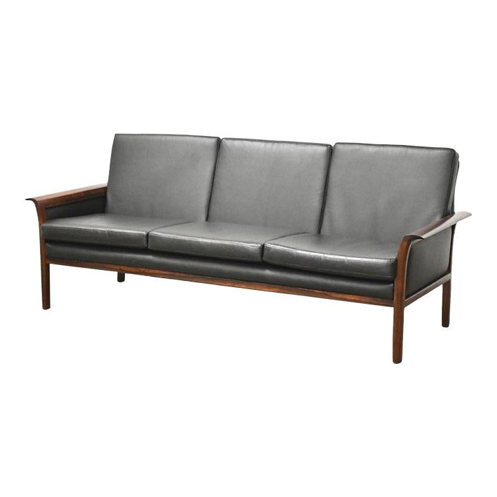 Knut Saeter Mid Century Black Vinyl Sofa with Rosewood Arms: Knut Saeter Mid Century Black Vinyl Sofa with Rosewood Arms Discover the elegance of mid-century modern design with this stunning black vinyl sofa featuring rosewood arms, crafted by Knut Saeter for V