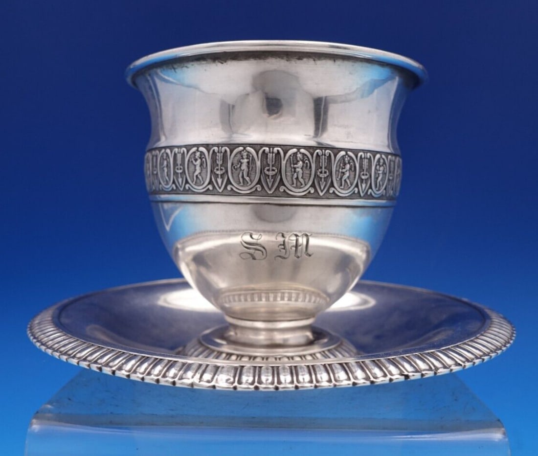 French Sterling Silver Cup and Saucer Set 2pc Cherub Design: French Sterling Silver Cup and Saucer Set 2pc Cherub Design This exquisite French sterling silver cup and saucer set, crafted between 1850 and 1899, features intricate details that highlight its remar