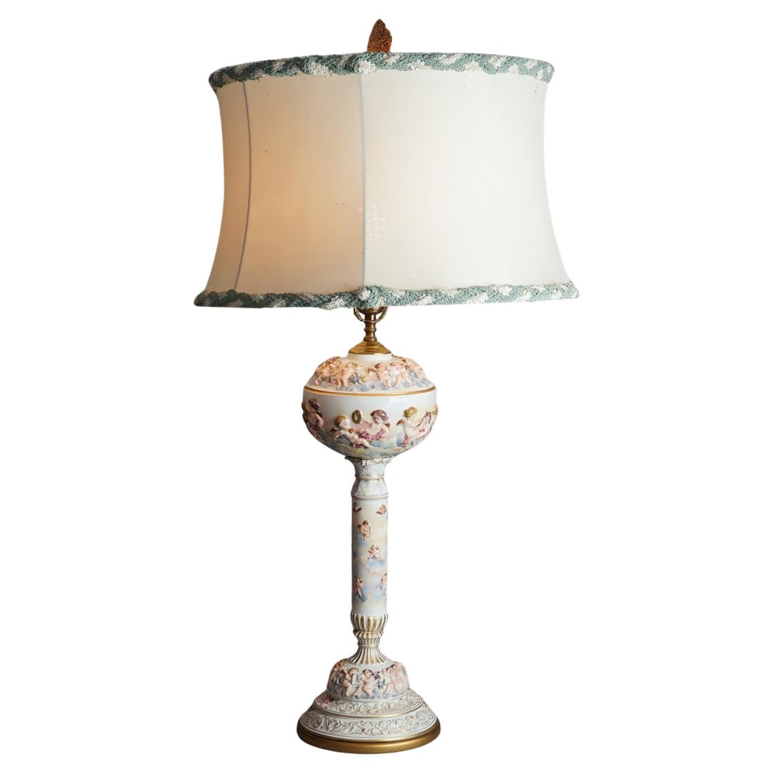 Porcelain Table Lamp With Embossed Cherubs Italian Classical Style Circa 1920: Porcelain Table Lamp With Embossed Cherubs Italian Classical Style Circa 1920 This antique table lamp from circa 1920 features finely embossed porcelain with hand-painted and gilt cherub motifs, showc