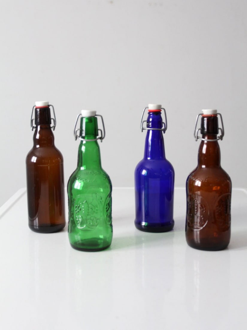 Set of 4 Vintage Swing-Top Glass Bottles in Mixed Colors: Set of 4 Vintage Swing-Top Glass Bottles in Mixed Colors Discover this charming set of four vintage swing-top glass bottles, featuring an attractive mix of amber, green, and cobalt blue colors. This c