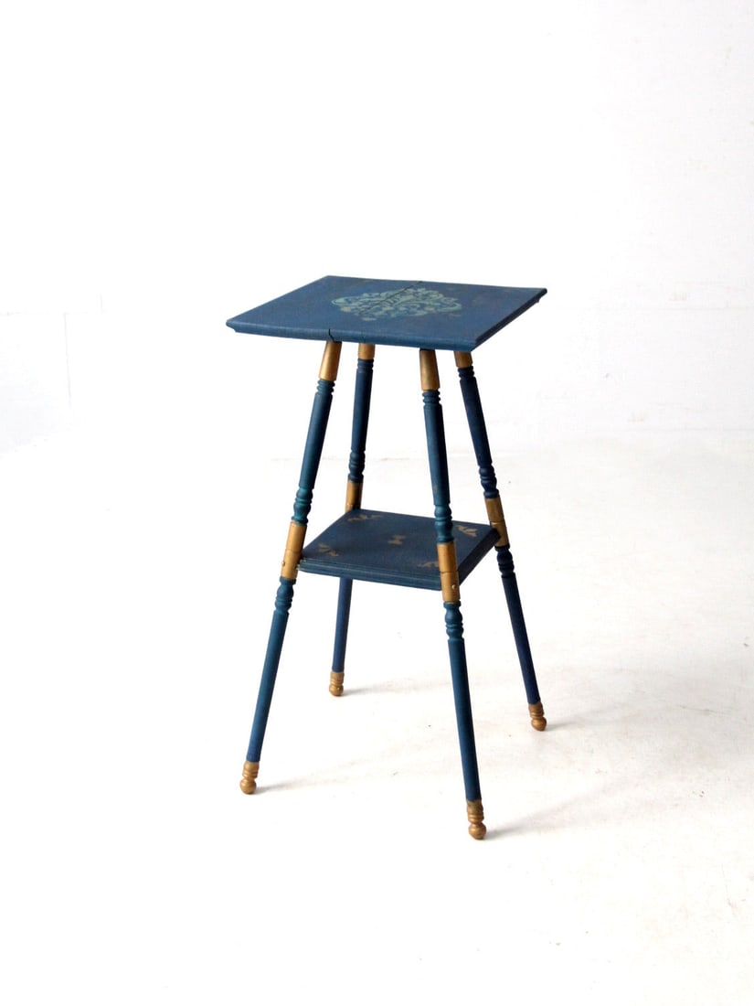 Charming Antique Blue Painted Accent Table with Gold Accents: Charming Antique Blue Painted Accent Table with Gold Accents This antique eclectic accent table showcases a charming worn blue painted finish adorned with delicate stenciled detailing. Its turned spla