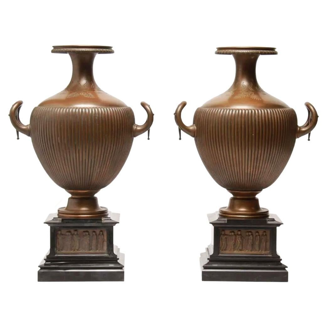 Set of 2 Greek Revival Bronze Hydra Water Jar Vases on Slate Bases: Set of 2 Greek Revival Bronze Hydra Water Jar Vases on Slate Bases This pair of Neoclassical vases is crafted from bronze in the form of Greek Hydra water jars, each set atop a slate base. Exhibiting 