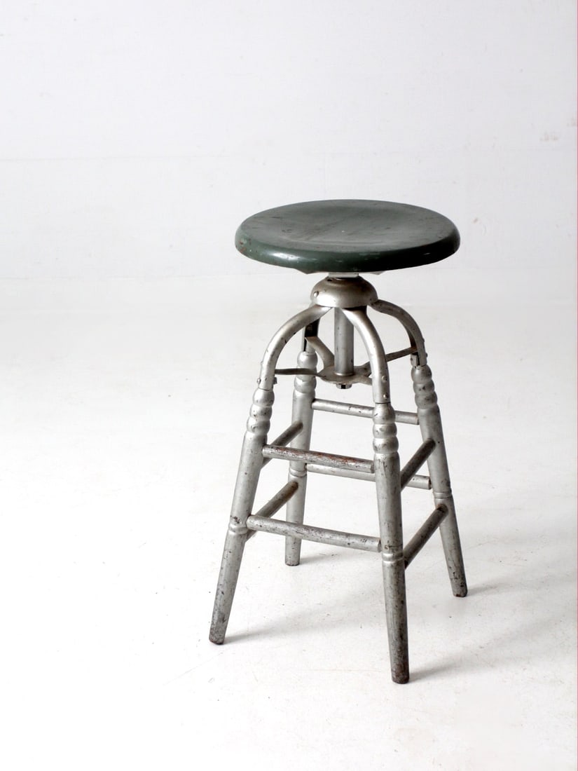 Antique Silver Painted Swivel Seat Stool with Green Round Seat: Antique Silver Painted Swivel Seat Stool with Green Round Seat This antique painted swivel seat stool features classic turned legs and a round green seat. The stool is finished with silver metallic pa