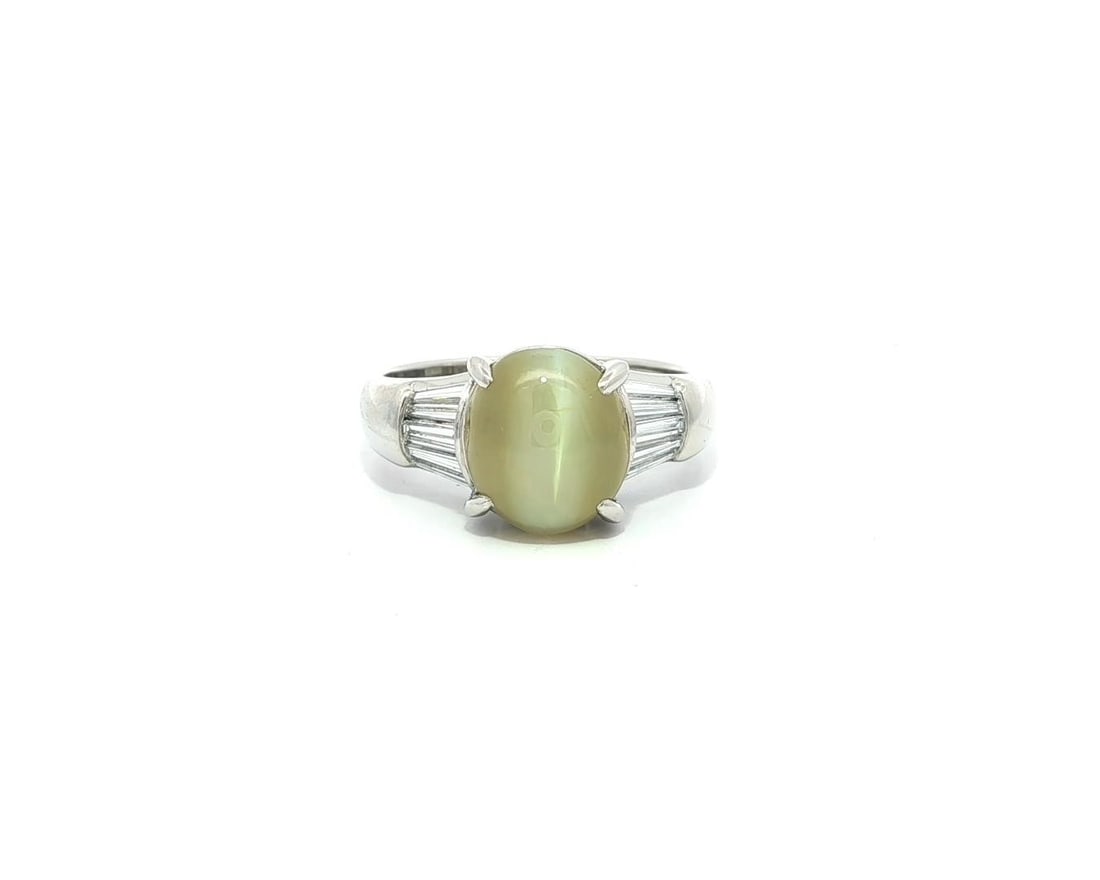 Platinum 4.28ctw Natural Cat's Eye Ring with Baguette Diamonds: Platinum 4.28ctw Natural Cat's Eye Ring with Baguette Diamonds This exquisite cocktail ring features a stunning natural cabochon cut Cat's Eye gemstone, showcasing a beautiful yellowish green hue. Set