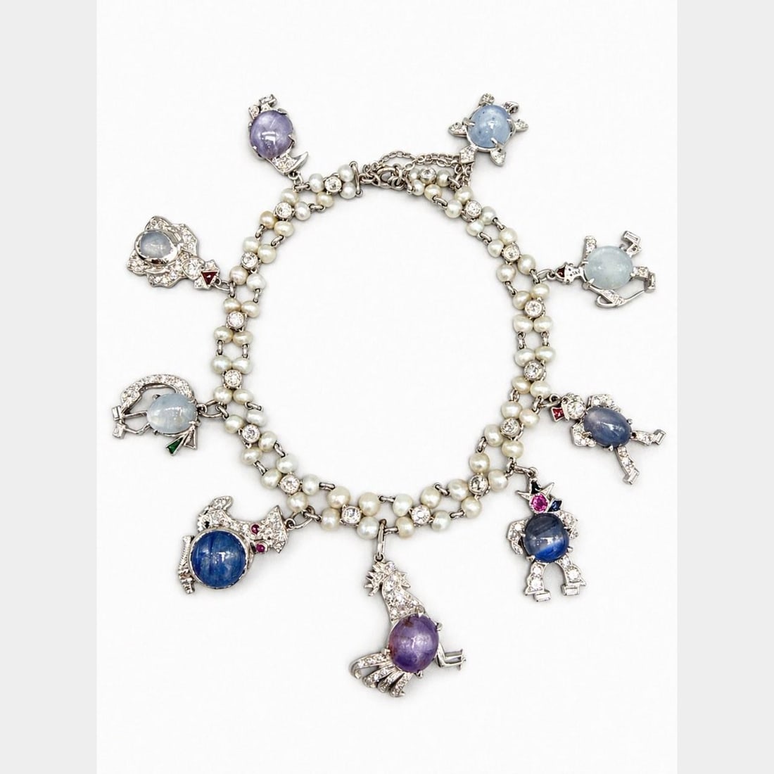 Platinum Charm Bracelet With Star Sapphires Diamonds and Natural Pearls Art Deco Era: Platinum Charm Bracelet With Star Sapphires Diamonds and Natural Pearls Art Deco Era This Art Deco charm bracelet features a platinum setting adorned with nine natural star sapphires totaling approxim