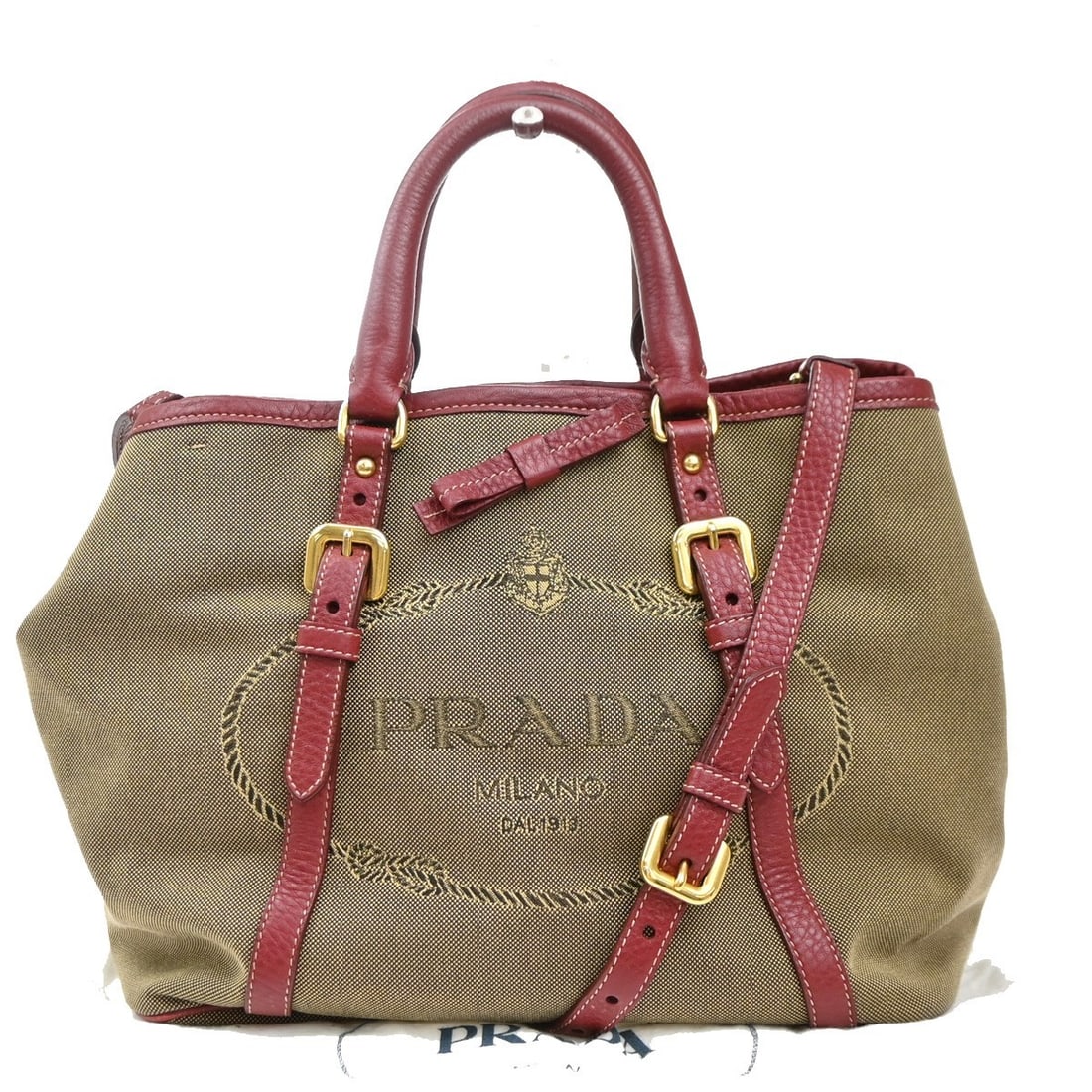 Beige Canvas Tote Bag by Prada with Leather Convertible Design: Beige Canvas Tote Bag by Prada with Leather Convertible Design This Prada Logo Convertible Tote for women features a beige canvas body complemented by leather accents. The tote measures 28cm x 23cm x 