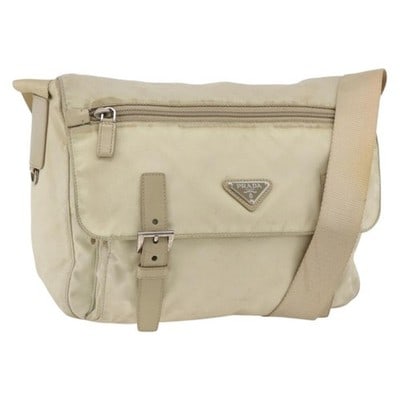 Prada beige nylon women shoulder bag with guarantee card: Prada beige nylon women shoulder bag with guarantee card This PRADA shoulder bag features a beige nylon exterior with silver-tone accents. Designed for practicality and style, it includes an adjustabl