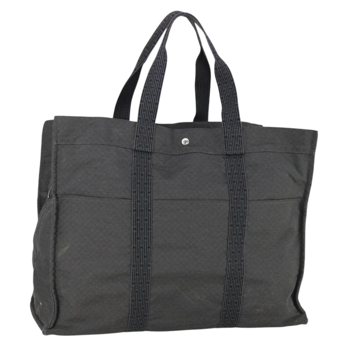 Her Line TGM canvas tote in gray and silver by Hermes France: Her Line TGM canvas tote in gray and silver by Hermes France This Hermes Her Line TGM hand bag is crafted from gray and silver canvas. The bag is heavily used and shows signs of wear, including loss o