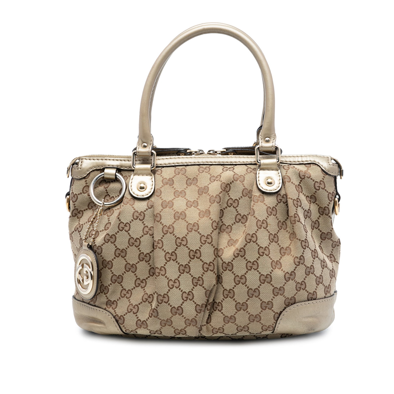 Beige GG Canvas Sukey Satchel by Gucci with Leather Handles: Beige GG Canvas Sukey Satchel by Gucci with Leather Handles The Gucci GG Canvas Sukey Satchel features a beige canvas body with rolled leather handles and a top zip closure. It is designed with interi