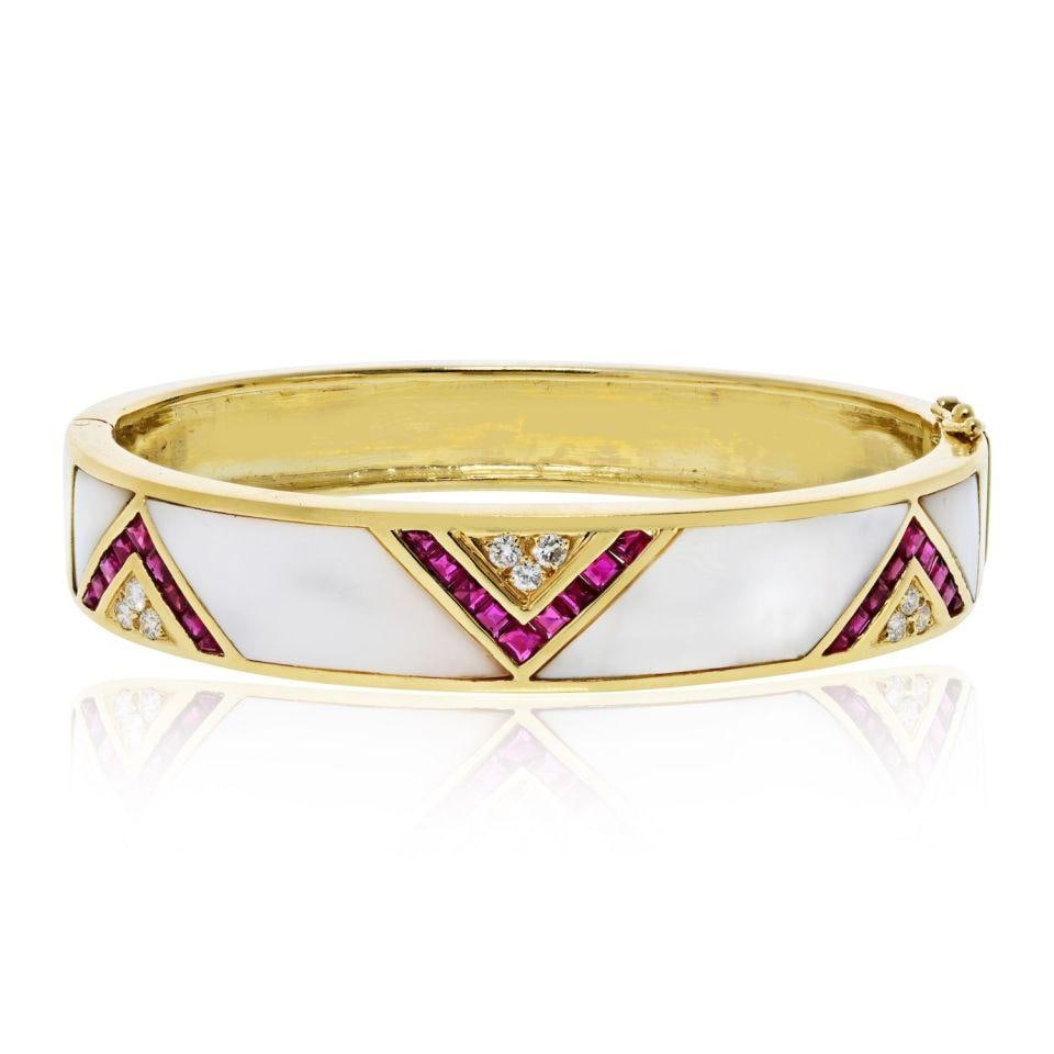 Geometric 18K Yellow Gold Bangle with Mother of Pearl Ruby and Diamond Accents: Geometric 18K Yellow Gold Bangle with Mother of Pearl Ruby and Diamond Accents This estate bangle bracelet is crafted from 18K yellow gold and features a sleek geometric design with polished mother of