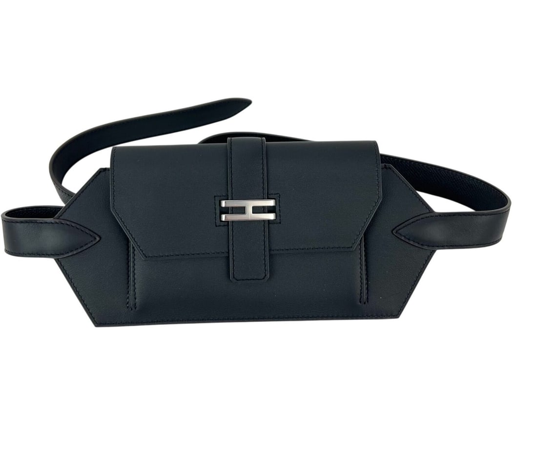 Hermes Elan 24 Black Leather Belt Bag with Box: Hermes Elan 24 Black Leather Belt Bag with Box This pre-owned Hermes Elan Pocket 24 belt bag is crafted from black Swift leather with a solid pattern and features a rectangular shape. The bag is desig