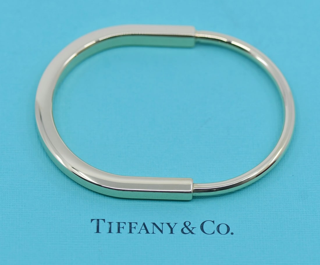 18K Yellow Gold XXL Lock Bangle Bracelet by Tiffany & Co: 18K Yellow Gold XXL Lock Bangle Bracelet by Tiffany & Co This Tiffany & Co. Lock bangle bracelet is crafted from 18k yellow gold and features a sleek, minimalist design. Sized XXL, it fits wrists up t