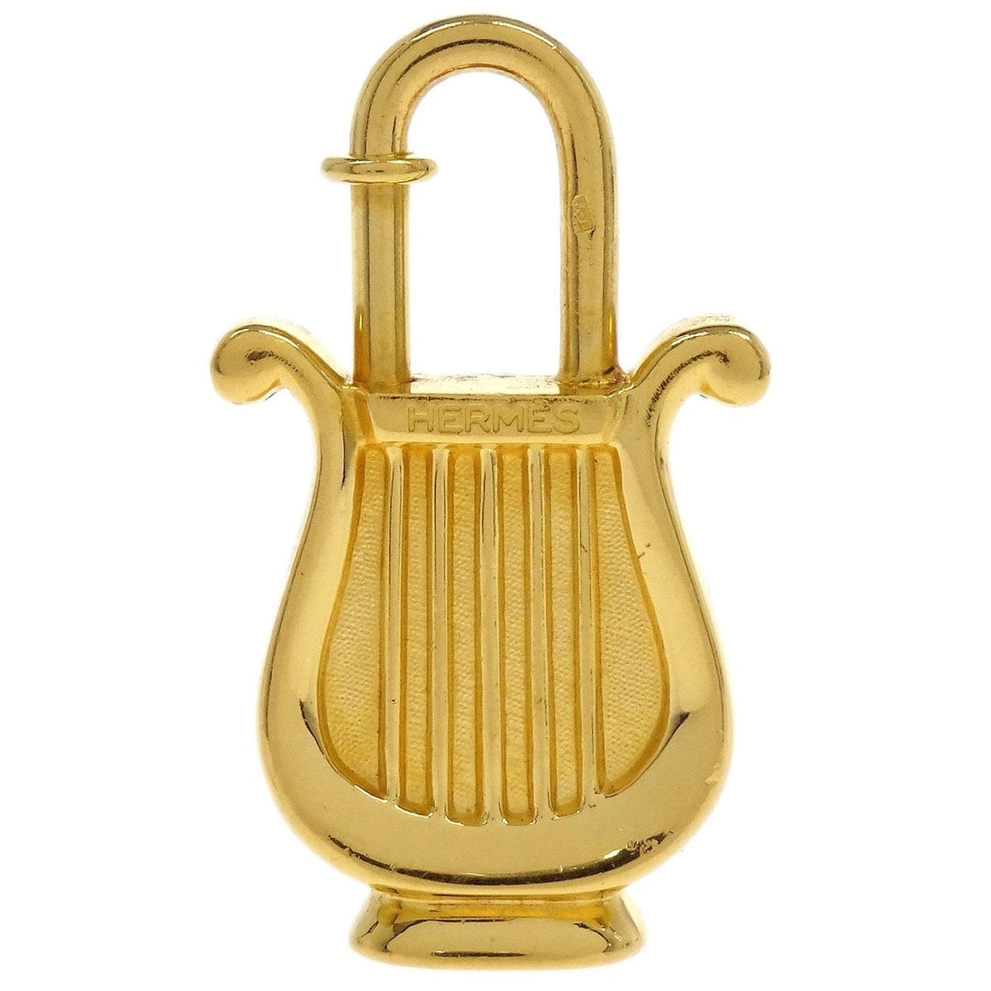 Gold Tone Hermes Harp Cadena Padlock Charm Vintage 1996: Gold Tone Hermes Harp Cadena Padlock Charm Vintage 1996 This is a vintage Hermes Harp 1996 Cadena padlock charm in a gold tone finish. Designed for unisex use, the charm displays a metal harp motif an