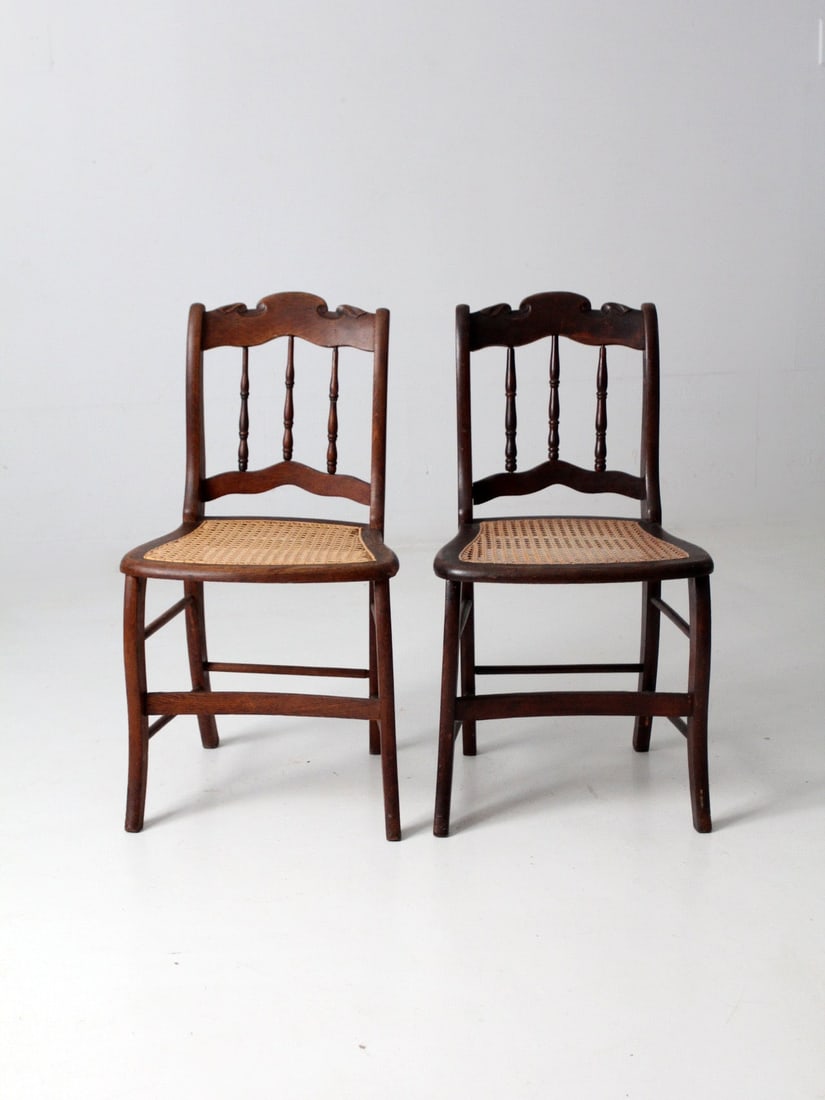 Pair of Antique Caned Seat Side Chairs with Bannister Backs: Pair of Antique Caned Seat Side Chairs with Bannister Backs This exquisite pair of antique wooden side chairs showcases elegant bannister backs and beautifully shaped rails. Each chair is designed wit