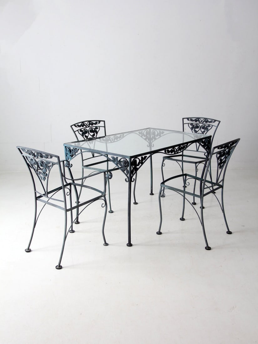 Vintage Wrought Iron Patio Set with Glass Top and Floral Design: Vintage Wrought Iron Patio Set with Glass Top and Floral Design Embrace the charm of outdoor dining with this Vintage American Garden Wrought Iron Patio Set, reminiscent of a quaint French bistro. Thi