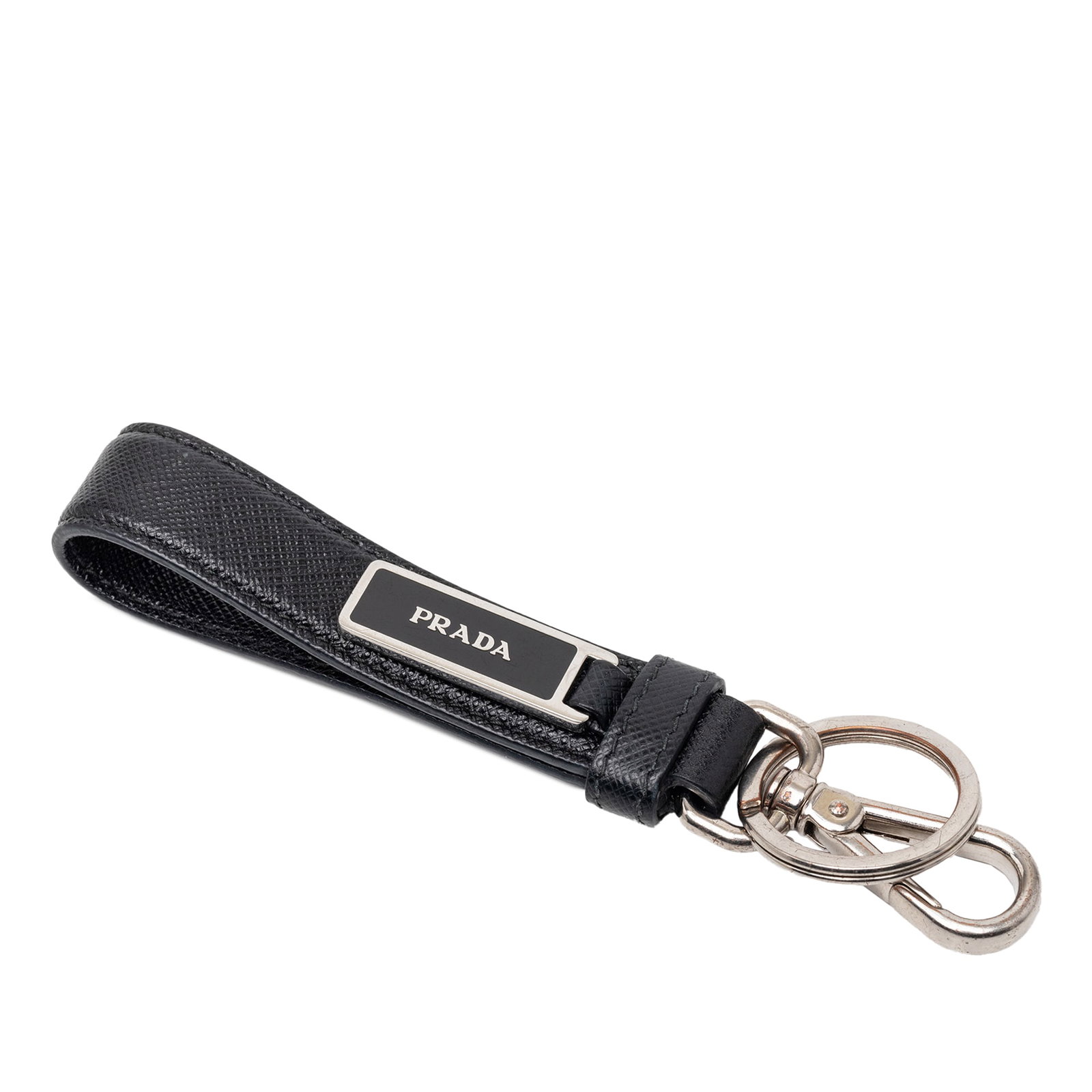 Black Saffiano Leather Key Chain with Silver Hardware by Prada: Black Saffiano Leather Key Chain with Silver Hardware by Prada This Prada Saffiano logo key chain features a saffiano leather body in black, complemented by silver tone hardware including a key ring