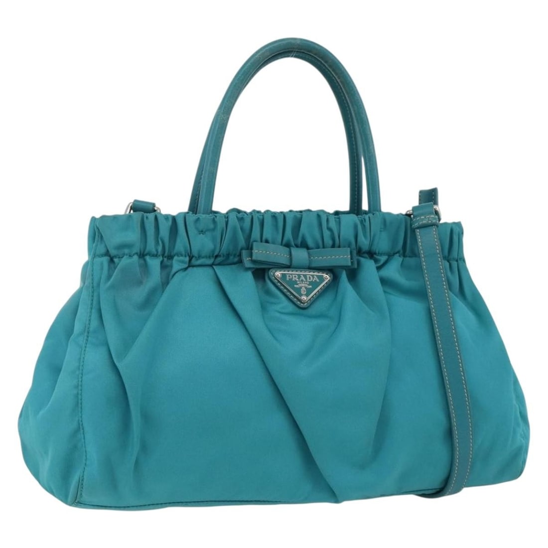 Prada turquoise blue nylon handbag with shoulder strap: Prada turquoise blue nylon handbag with shoulder strap This PRADA 2-way handbag is crafted from turquoise blue nylon with silver accents. Designed for versatility, it can be carried by hand or worn ov