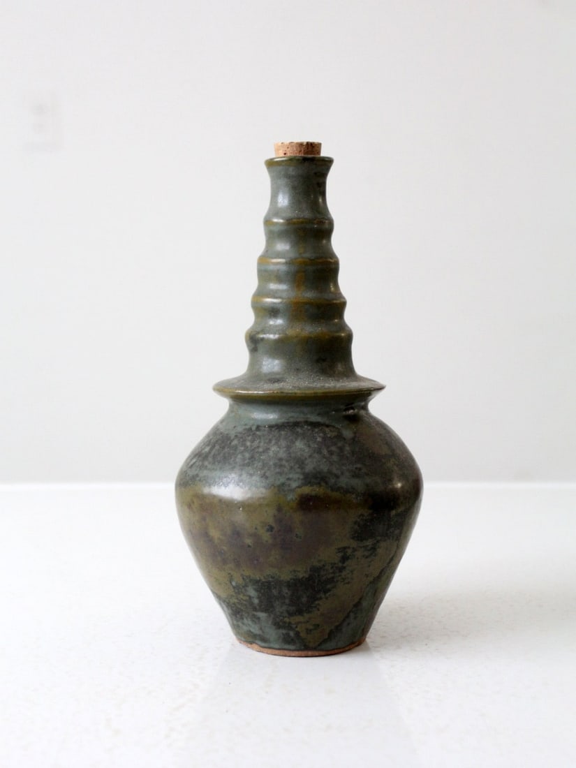 Signed Vintage Studio Pottery Vase with Green Black Glaze: Signed Vintage Studio Pottery Vase with Green Black Glaze This vintage studio pottery bottle vase showcases a unique handmade design, featuring a captivating green and black swirling glaze. It has a d