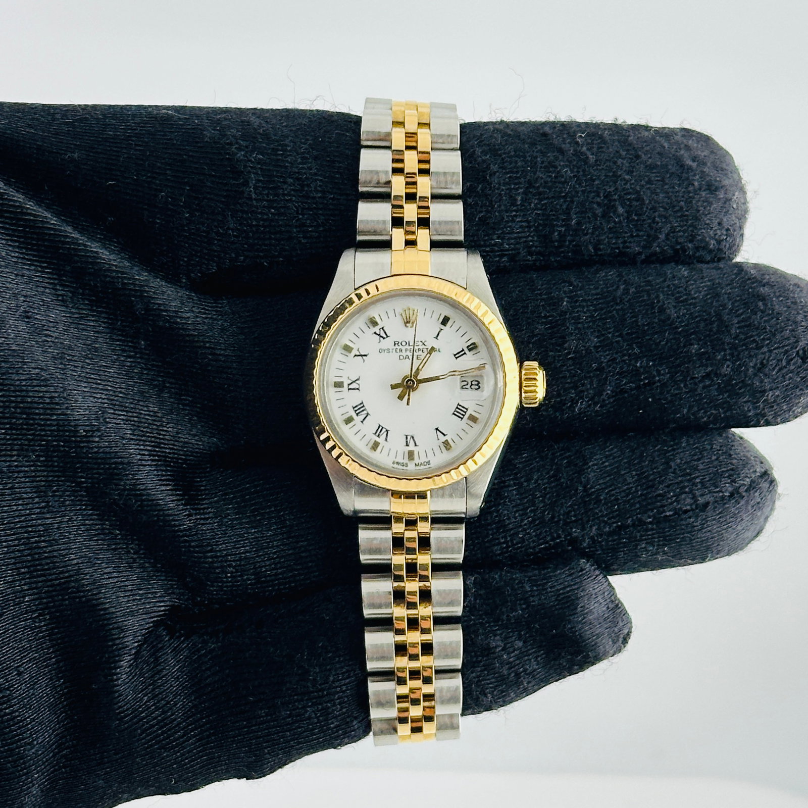Ladies Rolex Oyster Perpetual Date 6917 White Roman Dial Jubilee Bracelet: Ladies Rolex Oyster Perpetual Date 6917 White Roman Dial Jubilee Bracelet This Rolex Oyster Perpetual Date watch features a white dial with Roman numerals and gold markers, complemented by a fluted be