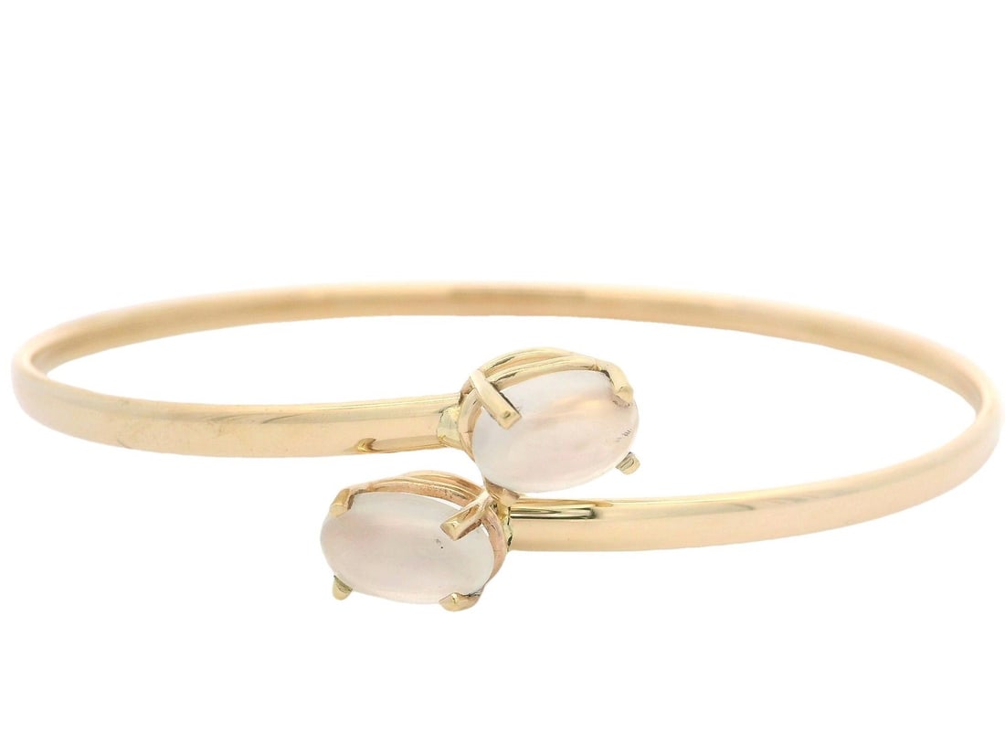 14k Yellow Gold Flexible Bypass Cuff Bangle with Blue Moonstone: 14k Yellow Gold Flexible Bypass Cuff Bangle with Blue Moonstone This exquisite cuff bangle features two natural genuine moonstones, each with an oval cabochon cut, prong set to showcase their stunning