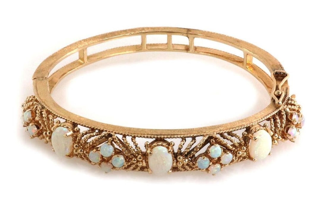 Vintage 14k Yellow Gold Fire Opal Floral Bangle Bracelet: Vintage 14k Yellow Gold Fire Opal Floral Bangle Bracelet This vintage bangle bracelet is crafted from 14k yellow gold and showcases a floral-inspired textured design. The centerpiece features an oval 