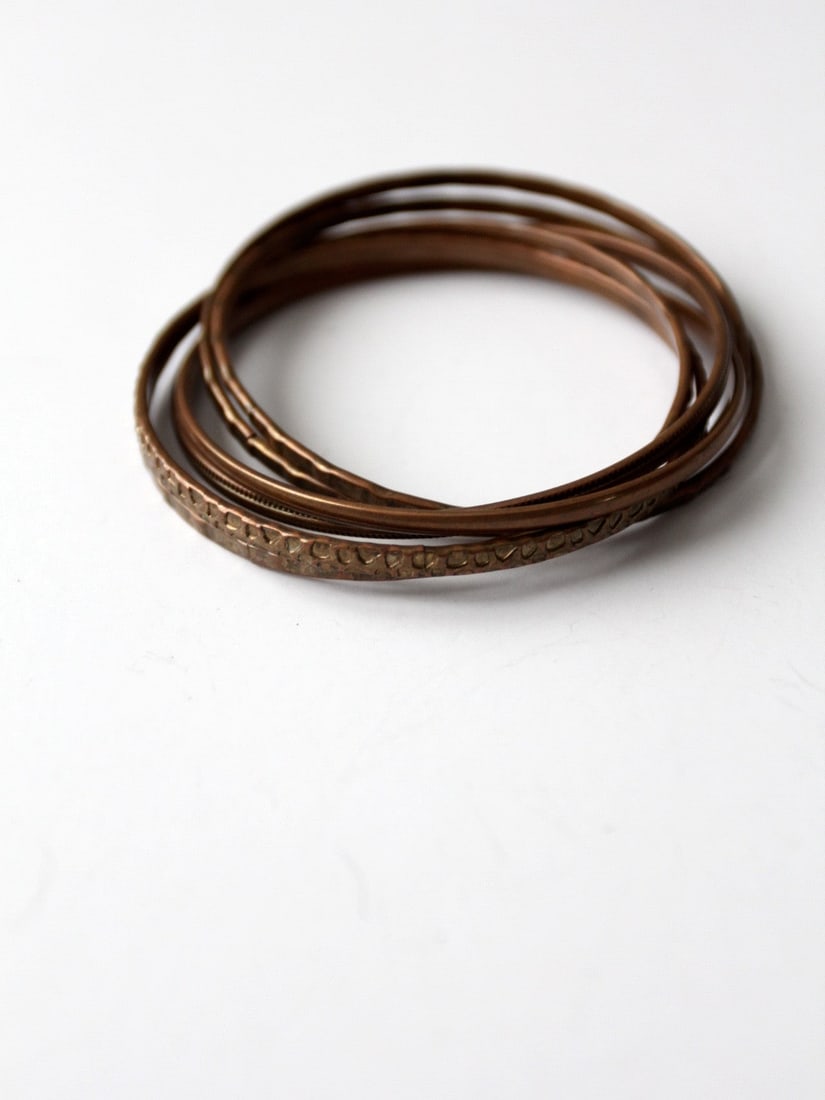 1970s Vintage Copper Entwined Bangle Set with Unique Designs: 1970s Vintage Copper Entwined Bangle Set with Unique Designs Introducing a stunning set of 1970s vintage copper entwined bangles, perfect for adding a touch of retro chic to any outfit. This unique br
