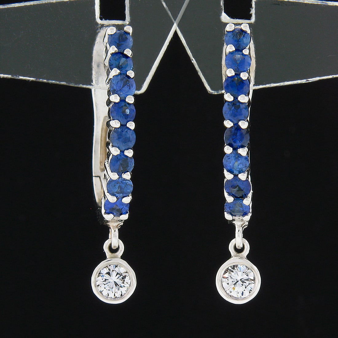 14k White Gold Sapphire Diamond Drop Hoop Earrings: 14k White Gold Sapphire Diamond Drop Hoop Earrings These custom-made drop hoop earrings are crafted from solid 14k white gold and feature a striking combination of natural gemstones. Each earring show