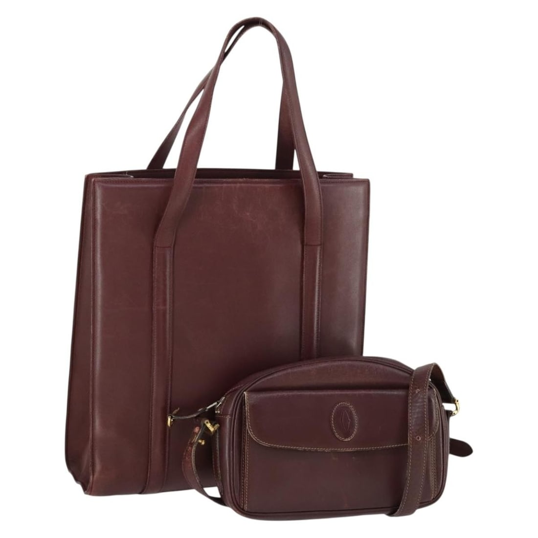 Set of 2 Cartier Must Line Bordeaux Leather Shoulder Bags with Guarantee Card: Set of 2 Cartier Must Line Bordeaux Leather Shoulder Bags with Guarantee Card This is a Cartier Must Line shoulder bag set crafted from leather in Bordeaux and gold tones. The bags are classified as h