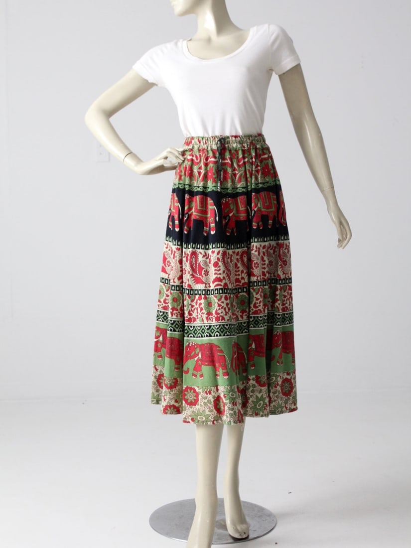 1970s Bohemian Elephant Print Cotton Skirt: 1970s Bohemian Elephant Print Cotton Skirt Embrace a touch of vintage flair with this 1970s bohemian skirt, showcasing a delightful elephant and floral block print in vibrant greens and reds. Crafted 