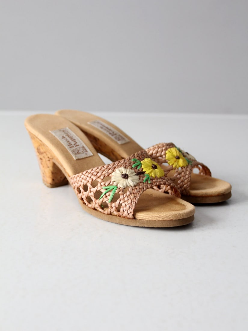 1970s Hush Puppies Floral Raffia Mules Cork Heels: 1970s Hush Puppies Floral Raffia Mules Cork Heels Step back into the 1970s with these charming Hush Puppies raffia mules. These stylish cork heeled slides feature open woven raffia uppers adorned with