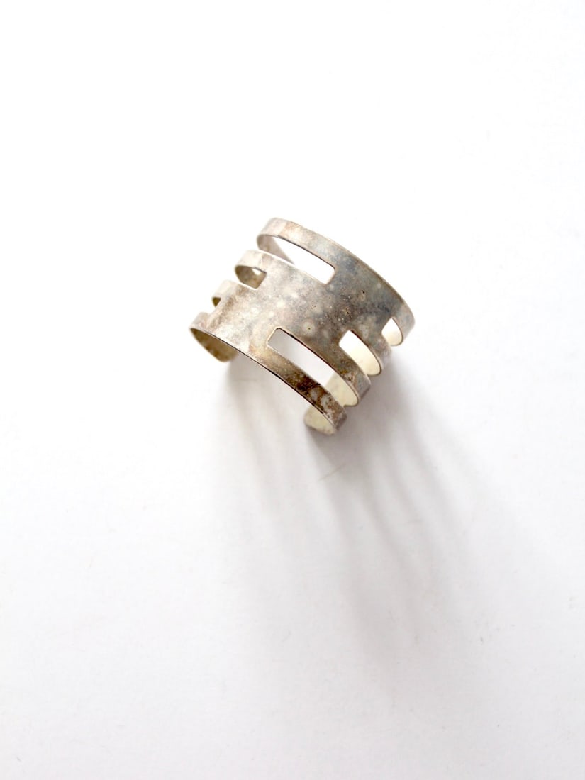 Vintage Modernist Silver Tone Cuff with Bold Cut-Out Design: Vintage Modernist Silver Tone Cuff with Bold Cut-Out Design This vintage modernist cuff showcases a striking wide silver tone bracelet with a bold cut-out design, perfect for making a statement. The p
