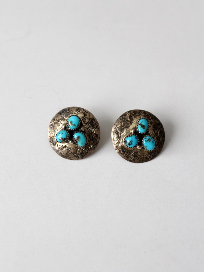 Sterling Silver Turquoise Sunburst Post Earrings Pair: Sterling Silver Turquoise Sunburst Post Earrings Pair This pair of vintage sterling silver earrings features intricately etched sunburst patterns and three inset turquoise stones on each earring. The 