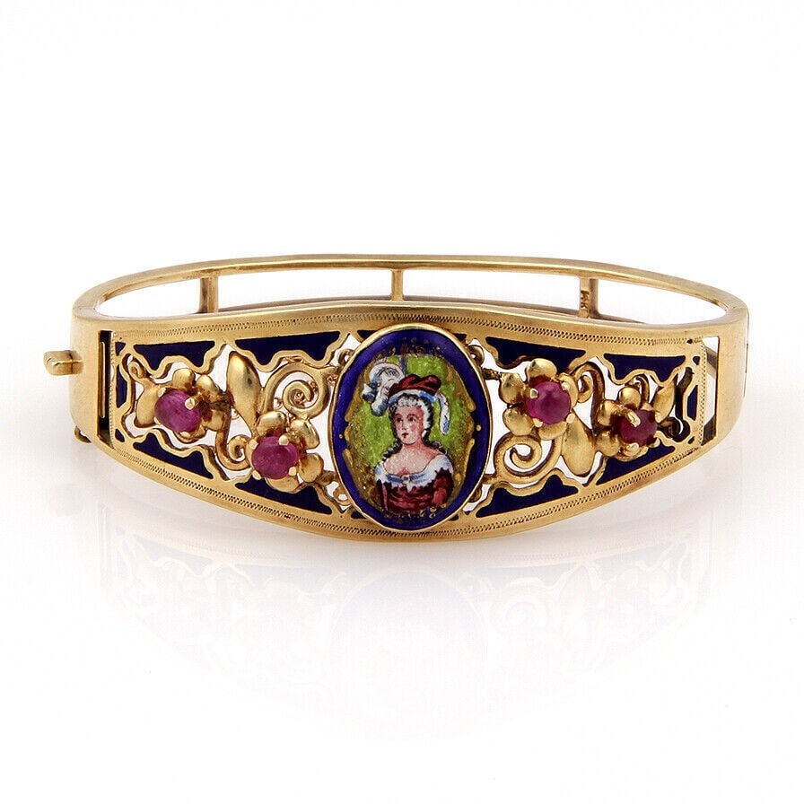 Vintage 14k Yellow Gold Portrait Bangle with Ruby Cabochons: Vintage 14k Yellow Gold Portrait Bangle with Ruby Cabochons This vintage hinged bangle bracelet is crafted from 14k yellow gold and features a finely painted porcelain portrait centerpiece. The portra