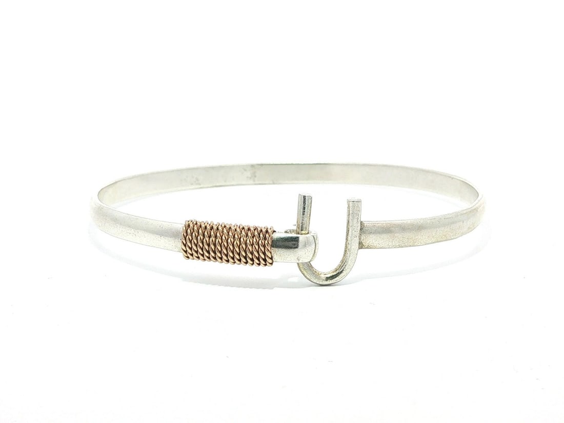 Sterling Silver Bypass Cuff Bangle with 14k Rose Gold Rope Accent: Sterling Silver Bypass Cuff Bangle with 14k Rose Gold Rope Accent This stylish bangle bracelet features a bypass cuff design crafted from sterling silver with a twisted rope wrap in 14k rose gold. The