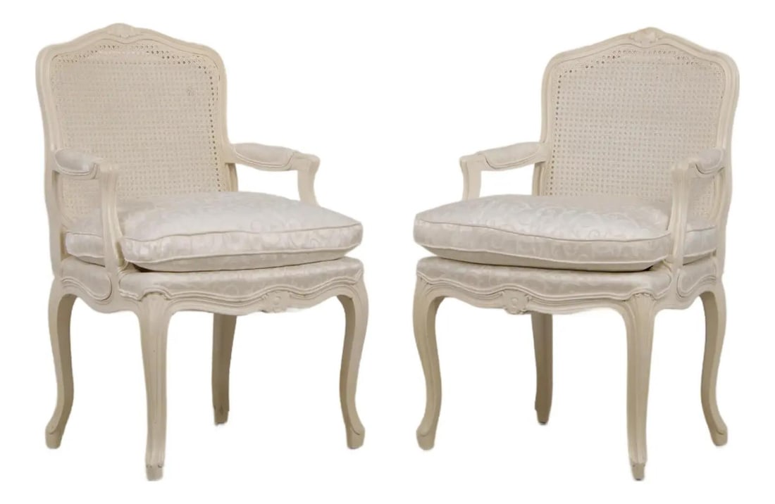 Louis XVI Painted Cane Back Armchair Pair: Louis XVI Painted Cane Back Armchair Pair This pair of Louis XVI style painted cane back fauteuil armchairs features finely carved wood frames, Queen Anne legs with pad feet, and clean, bright white d