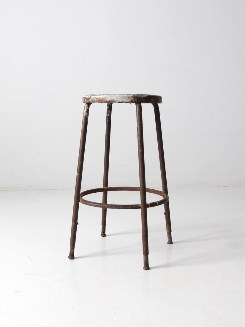 Midcentury Metal Workshop Stool With Steel Rod Base and Footrest: Midcentury Metal Workshop Stool With Steel Rod Base and Footrest This vintage industrial stool dates to the mid-20th century and features a circular metal seat, steel rod legs, and a ring footrest. Or