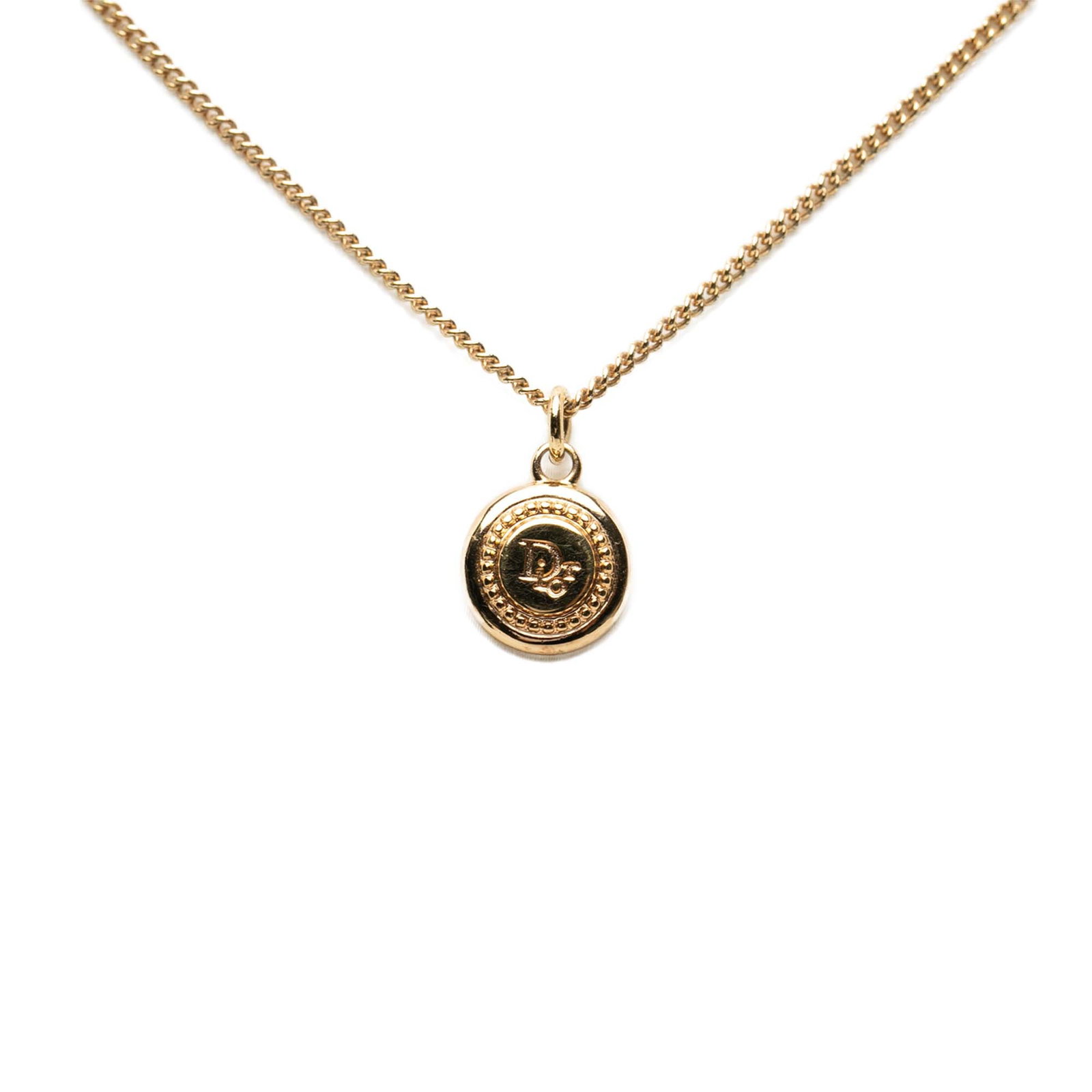 Dior Gold Tone Round Logo Pendant Necklace: Dior Gold Tone Round Logo Pendant Necklace This Dior necklace features a gold plated metal body with a gold tone round logo pendant and a secure lobster claw clasp. The piece is categorized as costume