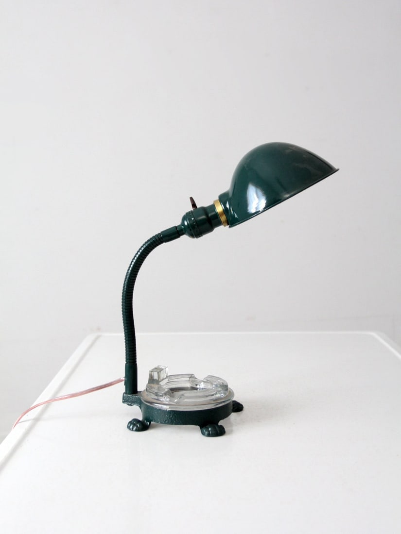 1930s Art Deco Desk Lamp Green Metal with Glass Ashtray Base: 1930s Art Deco Desk Lamp Green Metal with Glass Ashtray Base Vintage Art Deco desk lamp from the 1930s with a sculptural gooseneck design and deep green metal finish. It features a cast iron footed ba