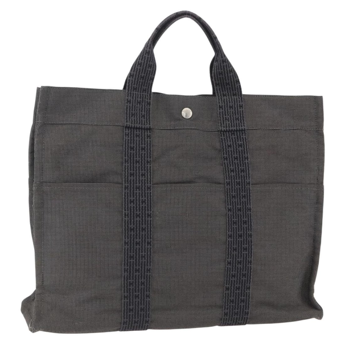 Gray Canvas Her Line MM Tote by Hermes France: Gray Canvas Her Line MM Tote by Hermes France This Hermes Her Line MM hand bag features a gray and silver canvas exterior and is made in France. The bag shows signs of heavy use, including out-of-shap