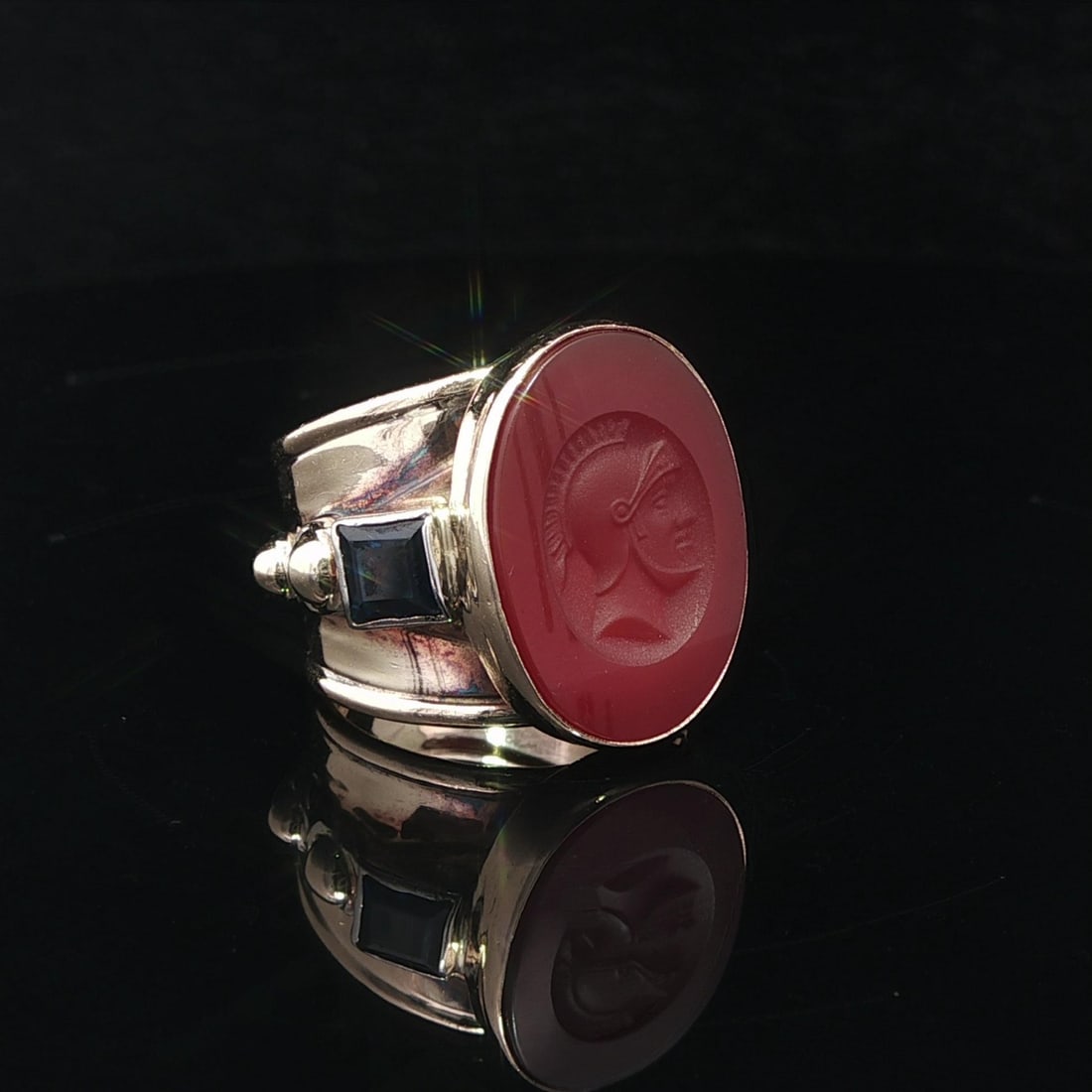 Wide Yellow Gold Intaglio Carnelian and Sapphire Signet Cigar Band Ring: Wide Yellow Gold Intaglio Carnelian and Sapphire Signet Cigar Band Ring This vintage signet ring features a wide cigar band design crafted from solid 12-14k yellow gold. The centerpiece is an oval-cut