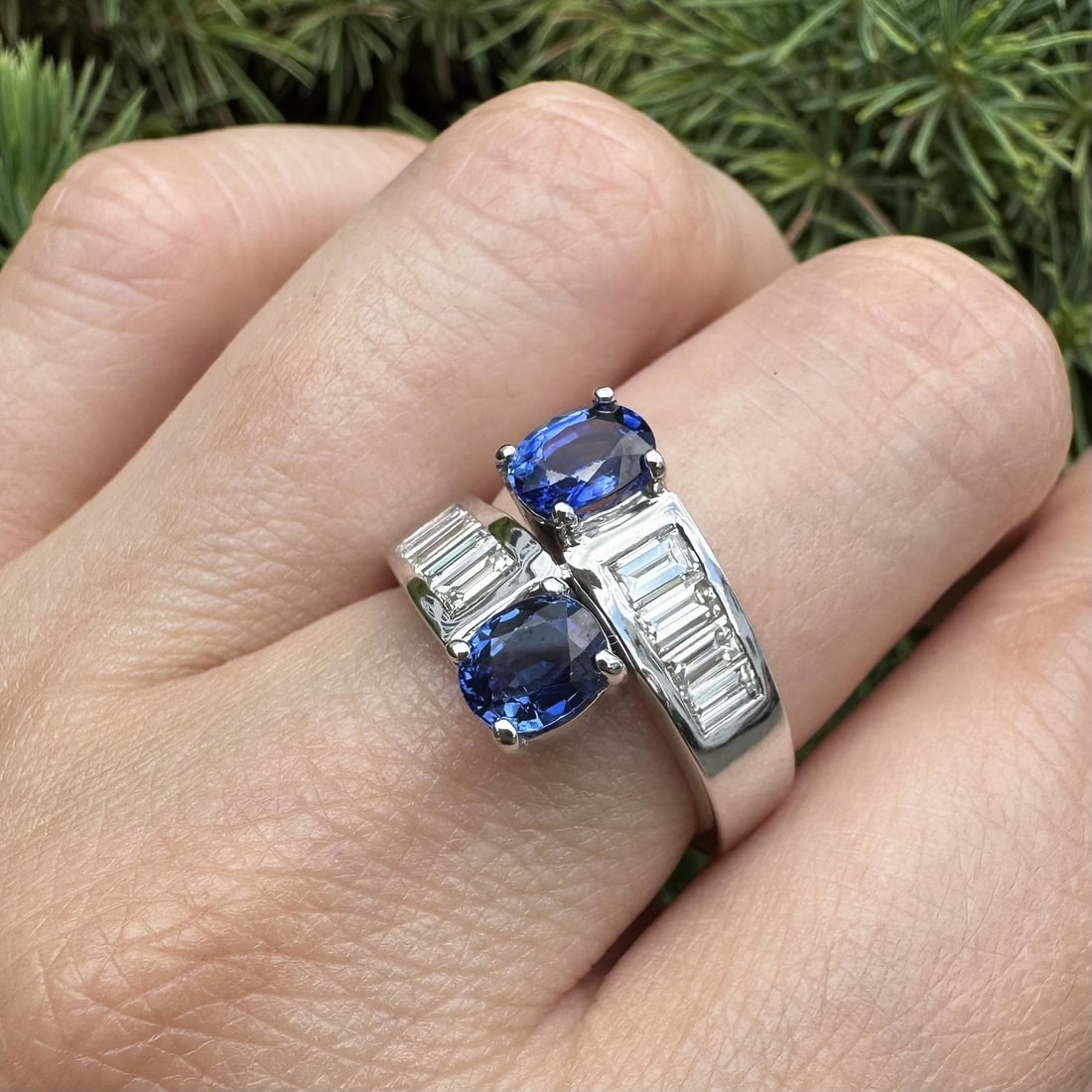 Oval sapphire bypass ring in 18k white gold with baguette diamonds: Oval sapphire bypass ring in 18k white gold with baguette diamonds This elegant bypass ring is crafted from solid 18k white gold and features two natural oval-cut sapphires in a striking royal blue hu
