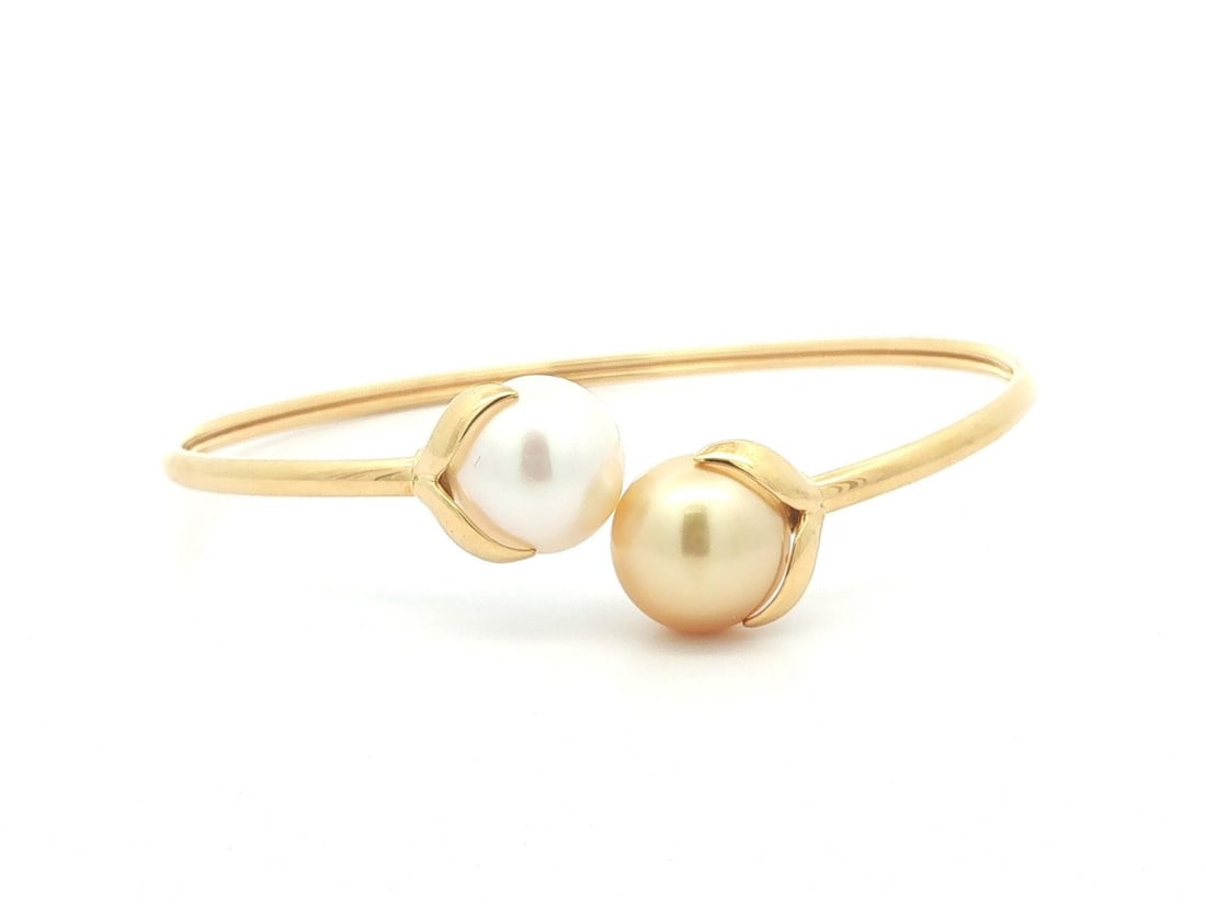Iridesse 18k Yellow Gold Cuff Bracelet with White and Golden Pearls: Iridesse 18k Yellow Gold Cuff Bracelet with White and Golden Pearls Elegant bypass cuff bangle bracelet crafted in solid 18k yellow gold and set with two cultured pearls in white and golden tones. Thi
