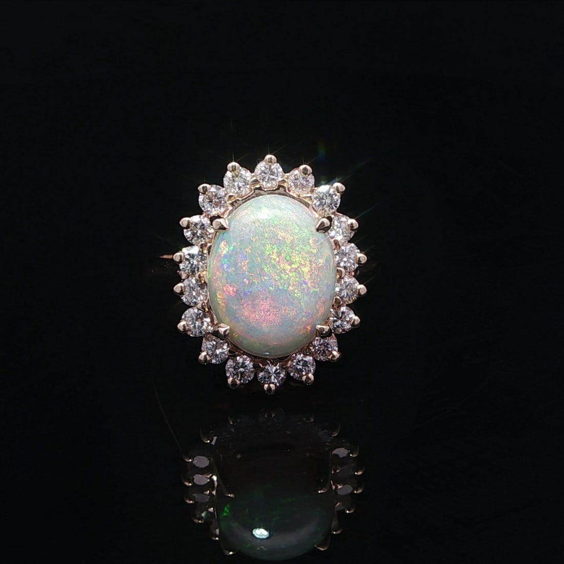 Yellow Gold Cocktail Ring With Opal Center and 1ct Diamond Halo: Yellow Gold Cocktail Ring With Opal Center and 1ct Diamond Halo This elegant cocktail ring features a large natural opal as its centerpiece, showcasing a beautiful play of colors. The opal is an oval 