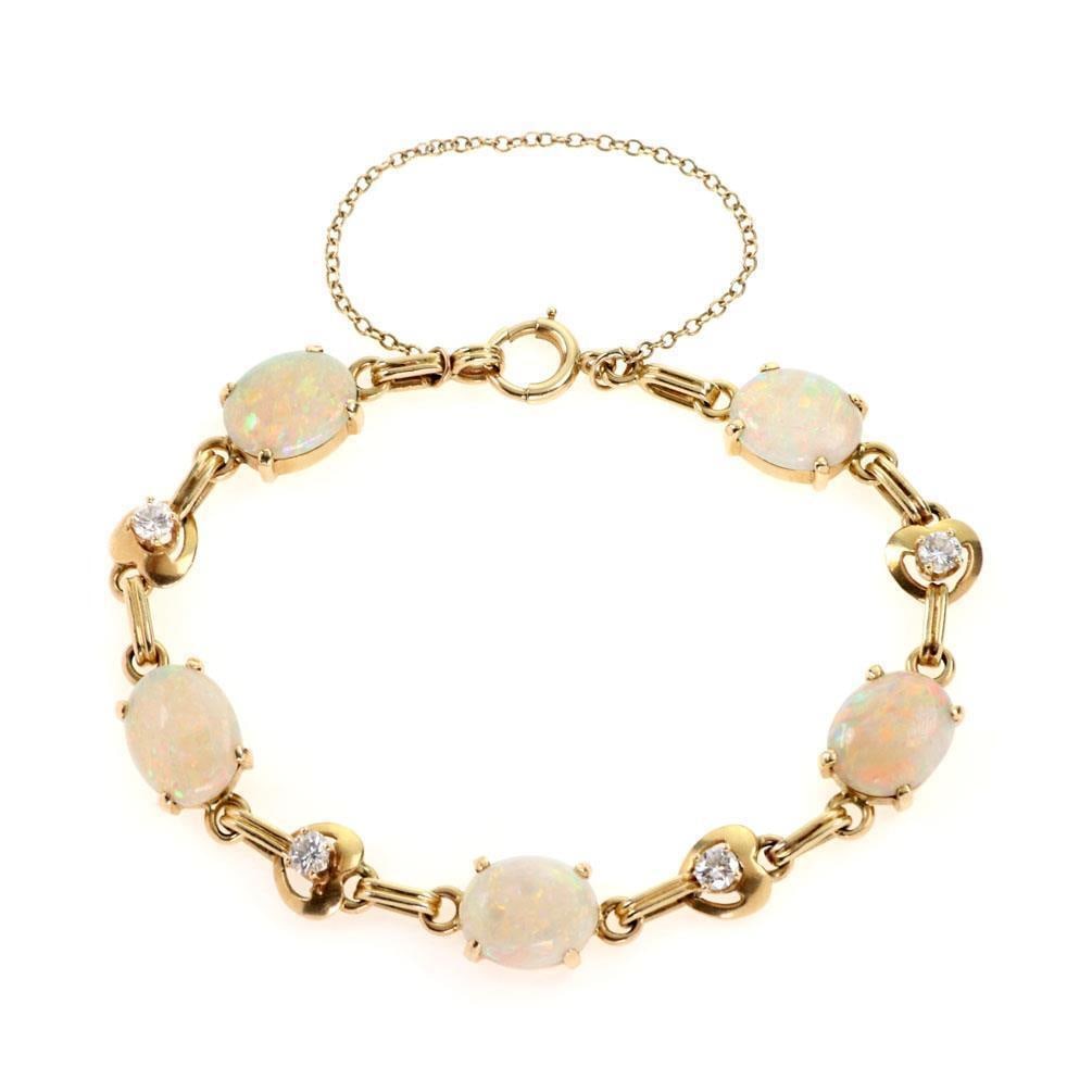 14k Yellow Gold Fancy Bracelet with Fire Opals and Diamond Accents: 14k Yellow Gold Fancy Bracelet with Fire Opals and Diamond Accents This exquisite 14k yellow gold bracelet features five stunning oval-shaped fire opals, beautifully complemented by four round cut dia