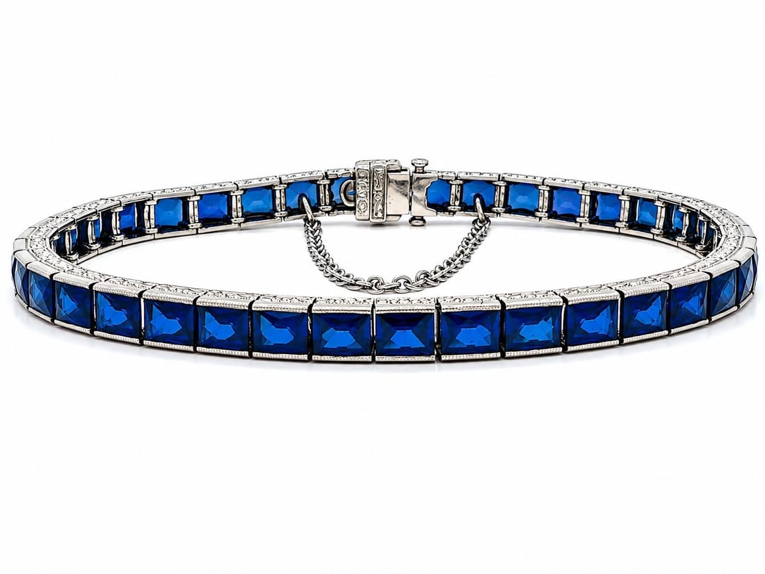 Art Deco Platinum Sapphire Line Bracelet GIA Maurice Tishman: Art Deco Platinum Sapphire Line Bracelet GIA Maurice Tishman This antique Art Deco line bracelet features forty rectangular French cut synthetic sapphires in a striking blue hue, securely set in a mil