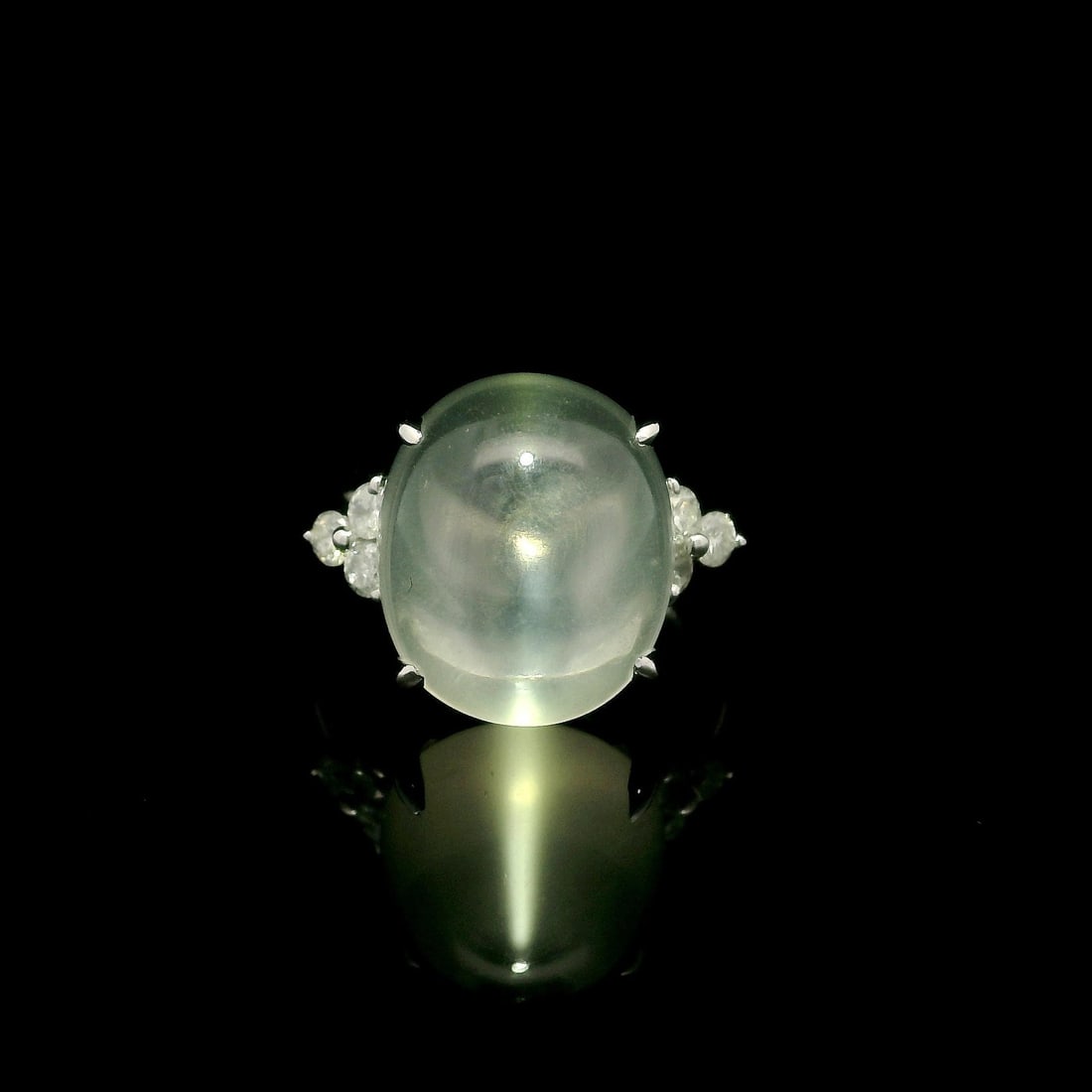 Large 10.31ctw Gray Cabochon Moonstone Diamond Sides Platinum Ring: Large 10.31ctw Gray Cabochon Moonstone Diamond Sides Platinum Ring This exquisite cocktail ring features a stunning large natural cabochon moonstone, displaying a mesmerizing grayish-white hue. The mo