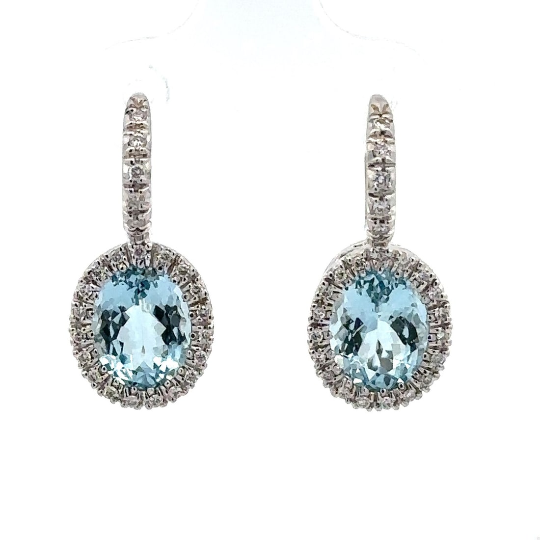 Natural Aquamarine and Diamond 18k White Gold Oval Halo Drop Earrings: Natural Aquamarine and Diamond 18k White Gold Oval Halo Drop Earrings These elegant dangle/drop earrings feature two natural oval-cut aquamarine gemstones with a vibrant blue color, each measuring
