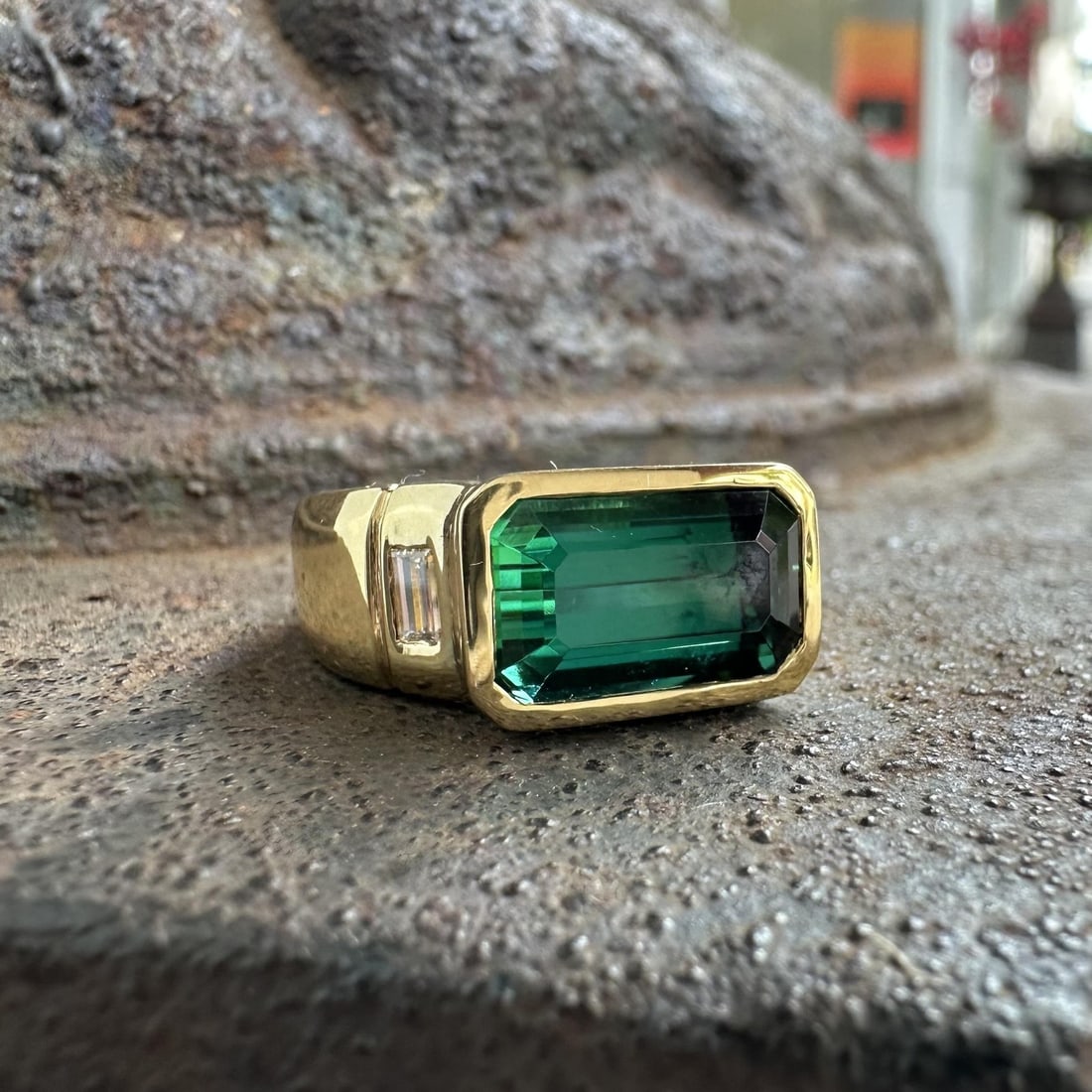 GIA 18k Yellow Gold East West Tourmaline Diamond Cocktail Ring: GIA 18k Yellow Gold East West Tourmaline Diamond Cocktail Ring This cocktail ring features a natural emerald-cut blue-green tourmaline set in a bezel setting, accented by two natural emerald-cut diamo
