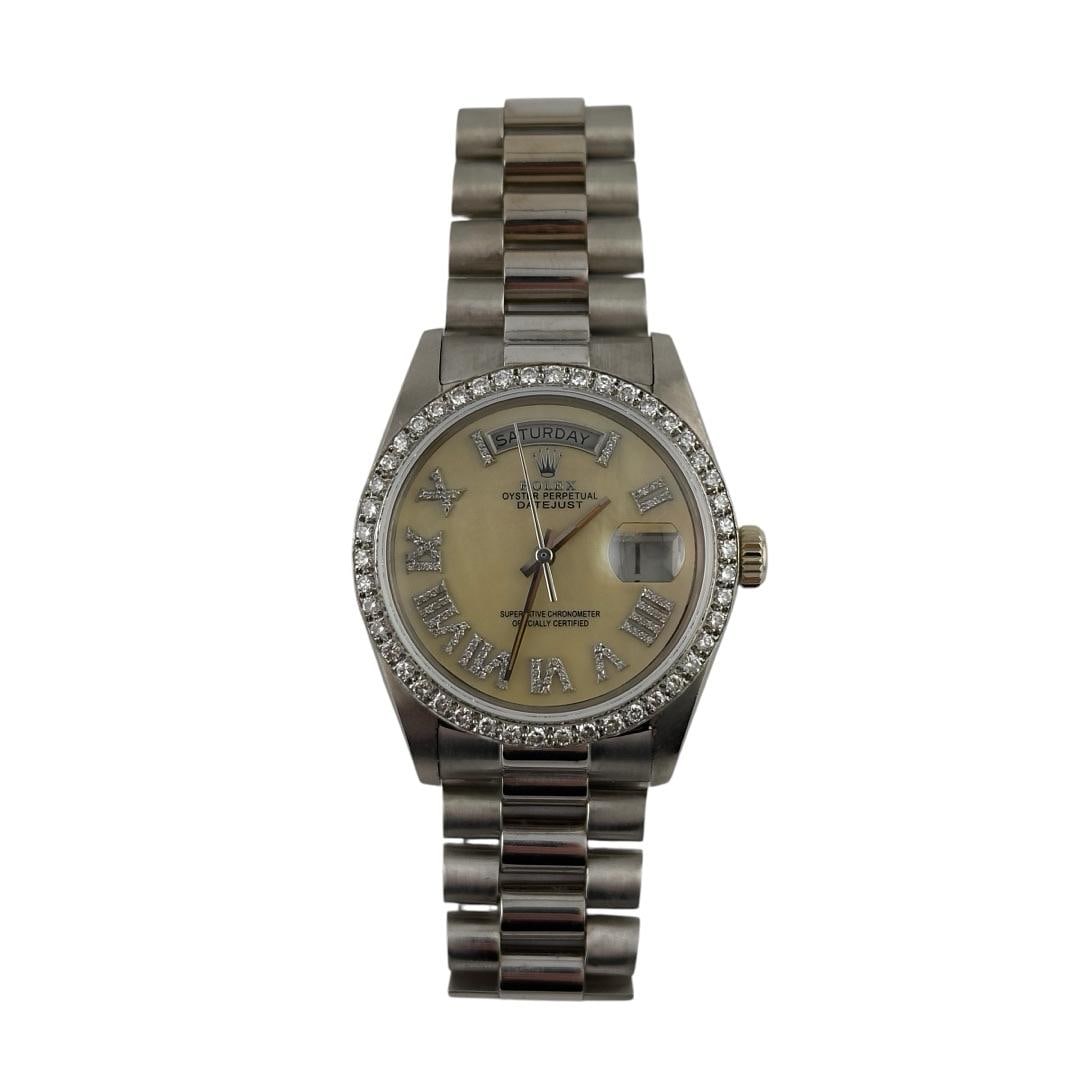 Rolex Day-Date 18039 Diamond Bezel President Bracelet MOP Roman Dial: Rolex Day-Date 18039 Diamond Bezel President Bracelet MOP Roman Dial This Rolex Day-Date features a Mother of Pearl Roman dial and is set on a President bracelet. The watch includes a diamond bezel an